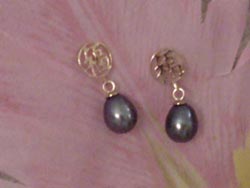 [ 6.5mm by 8.5mm oval black pearl earrings dangling from a 14K gold circle. ]